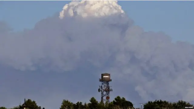 一股白烟从森林山火的上空升起