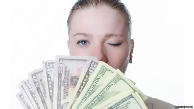 Una mujer detrás de un manojo de billetes