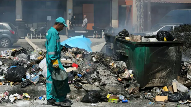 عامل تنظيف يحاول التعامل مع أكوام القمامة