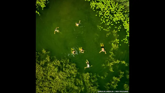 ’میں نے یہ تصاویر چار ماہ میں بنائی ہیں اور اس کے لیے میں نے سو سے زیادہ پروازوں کا استعمال کیا۔‘ یہ تصویر ليتھوینيا کی ایلکٹری نائی جھیل میں تیرتے ہوئے لوگوں کی ہے۔