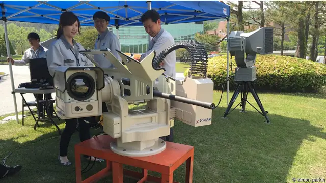 Сотрудники южнокорейской компании рядом с роботом-пулеметчиком