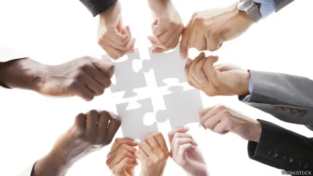 Varias manos armando un rompecabezas