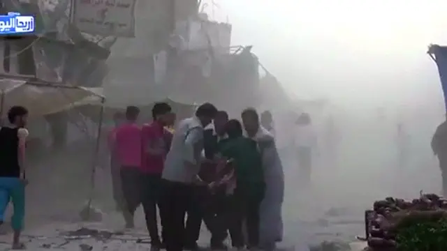 人们正在瓦砾中试图寻找幸存者，并抬出死者的尸体。