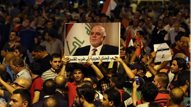 متظاهرون يرفعون صورة رئيس الوزراء العبادي في ميدان التحرير في بغداد تعبيرا عن تأييدهم لمقترحاته الرامية إلى مكافحة الفساد.