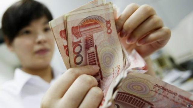 Una mujer cuenta billetes de yuan, la moneda china que se ha devaluado por tercer día consecutivo.
