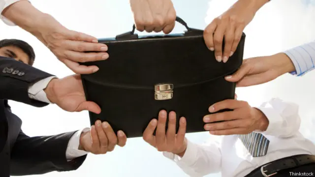 Equipo sujetando un maletin ejcutivo.