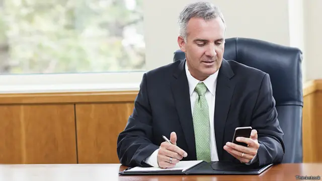 Бизнесмен внимательно смотрит на экран своего смартфона