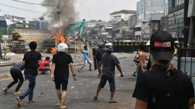 Aksi bentrokan warga dengan petugas keamanan menyebabkan terbakarnya backhoe yang digunakan untuk menghancurkan 150 rumah di pinggir sungai di Kampung Pulo, Jakarta, Indonesia. 