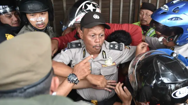 Polisi dan petugas keamanan tengah menahan seorang warga saat penghancuran 150 hunian di pinggir sungai di Kampung Pulo, Jakarta, pada 20 Agustus 2015.
