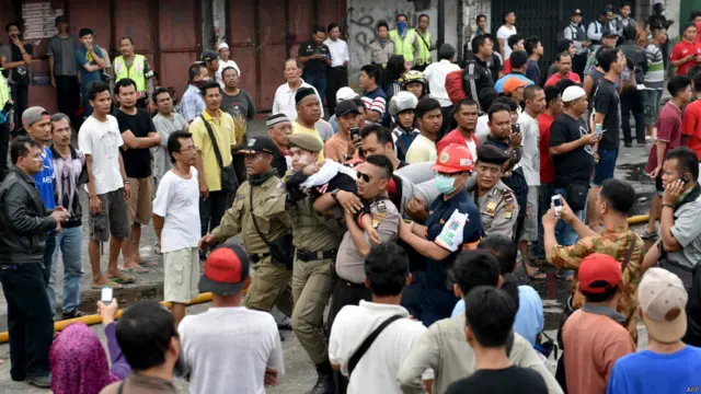 Petugas keamanan mengevakuasi korban luka saat terjadi penggusuran sekitar 150 hunian bantaran sungai di Kampung Pulo, Jakarta, 20 Agustus 2015. 