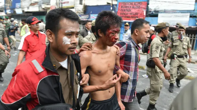 Polisi berpakaian preman dan petugas keamanan menahan seorang warga saat terjadi penggusuran dan penghancuran 150 hunian di bantaran sungai di Jakarta, 20 Agustus 2015. 