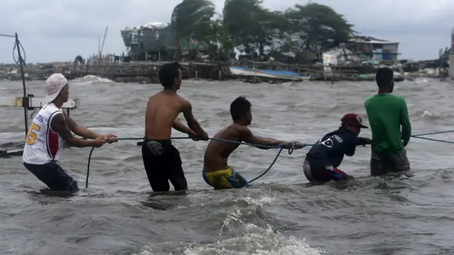 फिलीपिंस के मौसम विभाग ने देश में तूफ़ान की चेतावनी के स्तर को बढ़ा दिया है. राजधानी मनीला के उत्तर में नोवाटस शहर के तटीय गांव में मछुआरे बढ़ते समुद्री चल के बीच एक नाव को खींच रहे हैं.