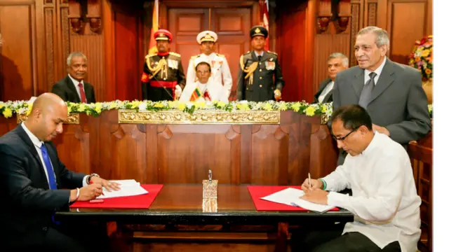 අගමැති දිව්රුම් දීමට සමගාමීව නව සම්මුතිවාදී ආණ්ඩුවේ ගිවිසුමට අත්සන් තබන එක්සත් ජාතික පක්ෂයේ සහ ශ්රීලනිප මහ ලේකම්වරුන් දෙදෙනා.