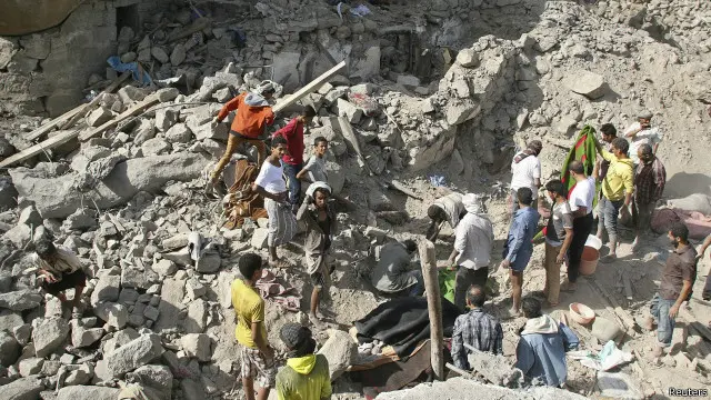 يمنيون وسط أنقاض منازل قيل إنها دمرت في غارات سعودية على مدينة تعز.