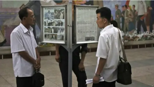 Başkent Pyongyang'da bir metro istasyonunda günlük gazeteyi okuyan Kuzey Koreliler. 