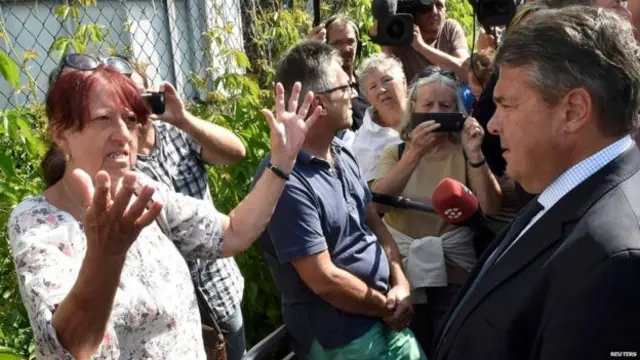 سیګمار ګابریل (ښۍ خوا ته) د سیمې خلکو سره خبرې وکړې او د پناه وړونکو استوګنځی يې هم ولید