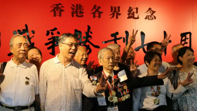 东江纵队老兵和参观民众在入口看板前比出胜利V字合影。