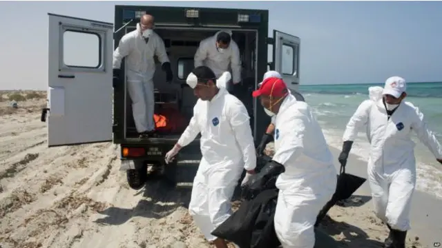 ماموران هلال احمر در ساحلی در زووارا اجساد قربانیان غرق دو قایق را منتقل می کنند