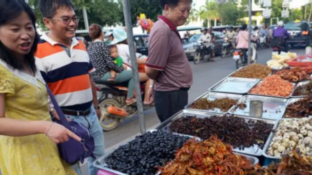 人們高興地從一盤盤的昆蟲裏挑選自己喜歡的美食(圖片來源：Tang ChhinSothy/AFP/Getty Images)