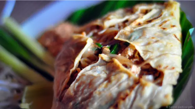 Tại quán Thip Samai, hay còn được gọi là quán Pad Thai Phratu Phi, tức là món Pad Thai cạnh cổng các hồn ma do quán nằm gần một đài hỏa táng, khách sẽ được dọn món ăn cuộn trong trứng tráng. Hương vị hài hòa hoàn hảo, với vị chua, ngọt, mặn, tất cả đều thấm đẫm, lại phảng phất thêm mùi khói than.