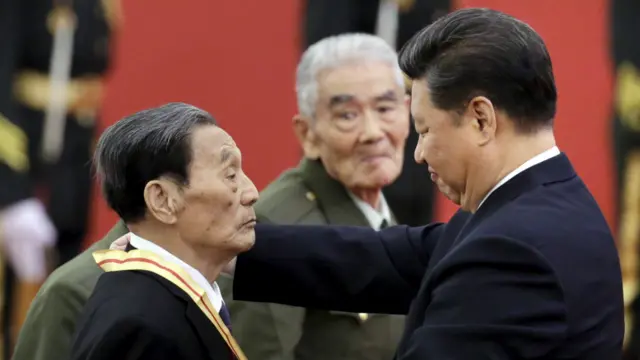 习近平为老兵颁发纪念章。