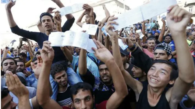 Budapeşt qatar stansiyasının qarşısında toplaşan miqrantlar biletlərini göstərirlər.