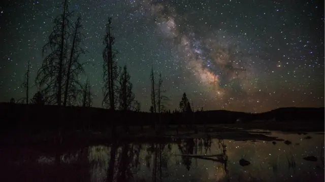 10. Wyoming, Hoa Kỳ: "Có một số địa điểm tối đen tuyệt đẹp tại vùng Tây Mỹ, quê tôi," Tiến sỹ John Barentine, quản lý chương trình tại Hiệp hội Bầu trời đêm Quốc tế (IDA) nói. "Đó là các công viên, hay các khu vực được bảo vệ như các khu bảo tồn tự nhiên. Các công viên quốc gia tại Mỹ và những nơi khác thường là những địa điểm tuyệt vời để khám phá bầu trời đêm hoang sơ, bởi chúng nằm cách xa thành phố và thường chưa phát triển nhiều về ánh sáng nhân tạo." Wyoming, nơi có cư dân thưa thớt và là nơi có Công viên Quốc gia Yellowstone, là một trong những bang nổi tiếng về vị trí đắc địa để quan sát bầu trời đêm. Hình: Lâu đài Geyser ở Công viên Quốc gia Yellowstone Wyoming, Hoa Kỳ.