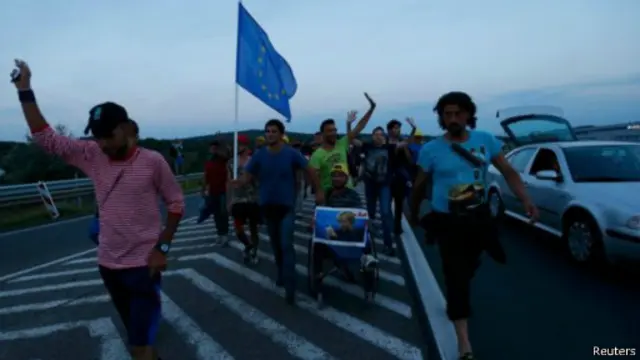 幾名難民手持德國總理默克爾的大幅照片