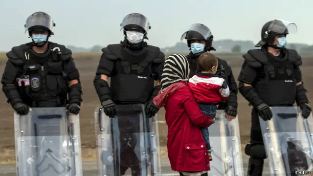 一名女子手抱幼儿站在防暴警察队列前