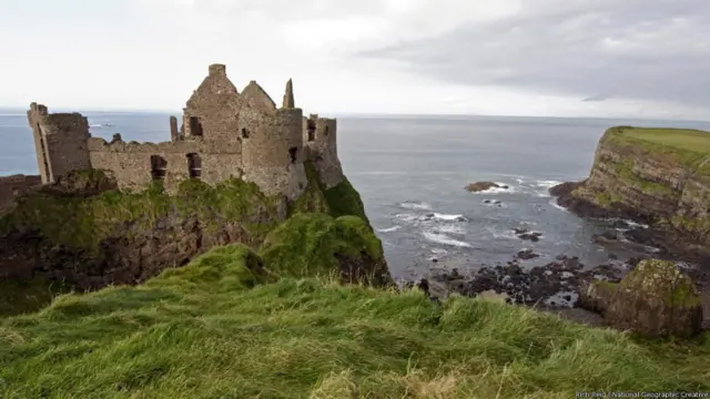 Terletak di pinggiran desa kecil Portballintrae, bertengger di atas bukit batu basal yang seakan bisa longsor sewaktu-waktu, Kastil Dunluce adalah salah satu reruntuhan tertua di County Antrim. Catatan menunjukkan bahwa kastil ini dibangun pada tahun 1500 oleh wangsa McQuillans, sebuah keluarga yang berkuasa waktu itu, yang berasal dari barat daya Skotlandia. Mereka pertama kali tiba di Irlandia Utara di tahun 1200 sebagai tentara bayaran. Kediaman abad pertengahan itu menjadi salah satu penyebab dalam konflik di tahun-tahun pergolakan, dengan pertempuran yang paling menentukan atas tanah itu terjadi 1565. Pada tahun 1554, datang Wangsa MacDonnells dari Islay. Ini wangsa yang masih terkait secara silsilah dengan Wangsa Donald dari Highland Skotlandia. Di bawah kepemimpinan Sorley Boy MacDonnell - kepala wangsa dan pemegang kekayaan wangsa itu - mereka mengepung benteng itu selama Pertempuran Orla, dan merebut kepemilikan benteng. Selama abad berikutnya, terjadi berbagai upaya untuk menjatuhkan kekuasaan wangsa MacDonnells atas benteng itu, dan keluarga itu akhirnya hengkang di pertengahan abad16, meninggalkan benteng Dunluce yang kian lama kian jadi puing. 
