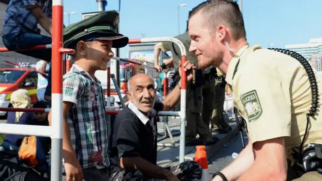 Almaniyaya xoş gəlmisiz: yeni gəlmiş uşaq polis papağını yoxlayır