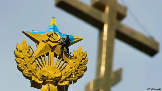 Рабочий закрашивает звезду на высотке