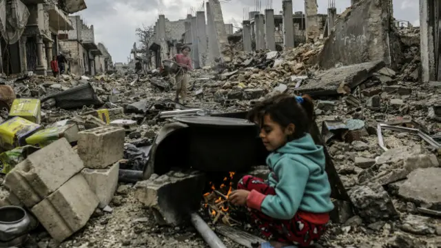 叙利亚科巴尼的废墟中一名女孩坐在瓦砾上生火取暖（22/3/2015）