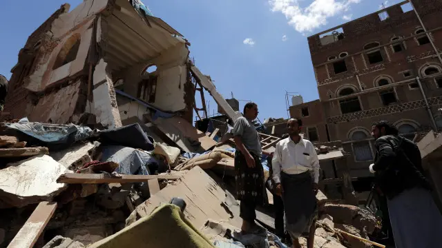 يمنيون وسط أنقاض منزل قيل إنه تهدم جراء غارات سعودية على العاصمة صنعاء.