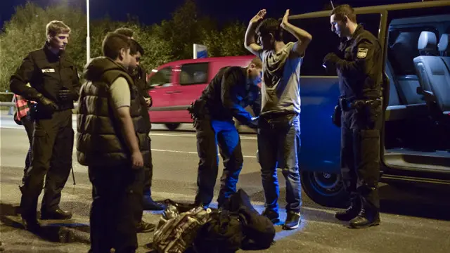 یک پلیس آلمانی در حال بازرسی یکی از پناهجویان سوری