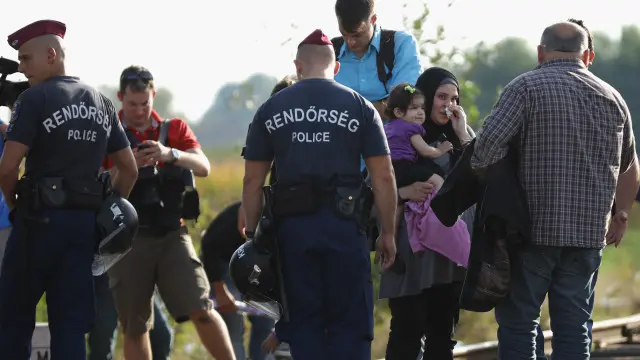 بہت سے لوگ اس خار دار باڑ کو عبور کرنے کا راستہ تلاش کر رہے ہیں جبکہ دیگر لوگ احتجاجاً کھانے پھینک رہے ہیں