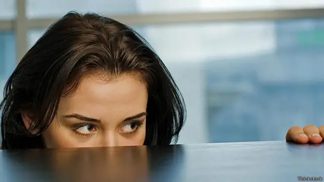 Девушка прячется за рабочим столом