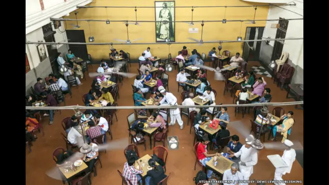 Abokan ciniki zaune kusa da inda aka makala hoton Rabindranath Tagore a shagon shan shayi na Kolkata a Indiya.