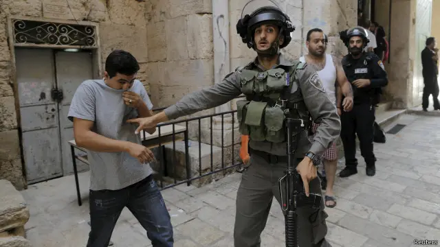 جندي إسرائيلي يمنع فلسطينيا من دخول المنطقة التي يقع فيها المسجد الأقصى.