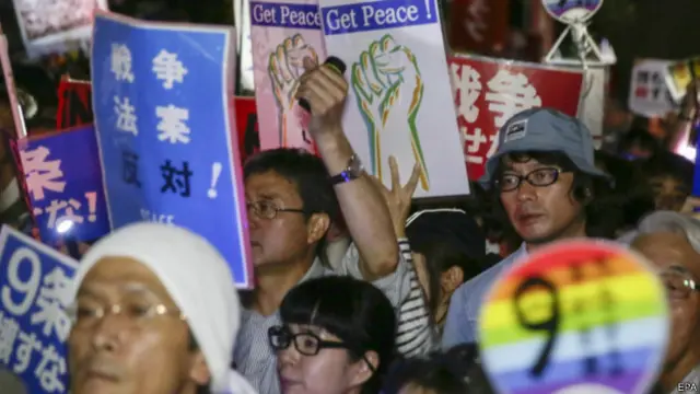 在日本国会外，成千上万的示威人群冒雨集会，抗议通过安保法案。