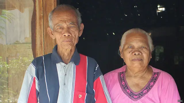 Radimin bersama istrinya di depan rumahnya tidak jauh dari lokasi pembantaian.