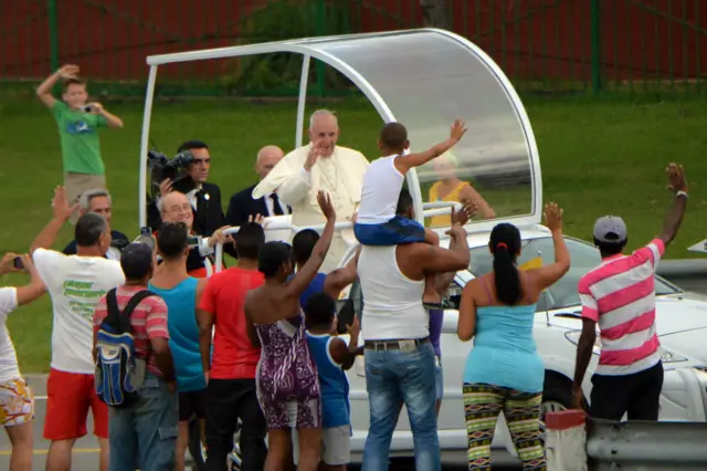 El papa Francisco saluda a personas que esperaban para verlo durante su recorrido.