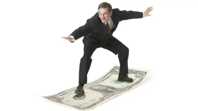 Un hombre de negocios hace "surf" en un billete de un dólar