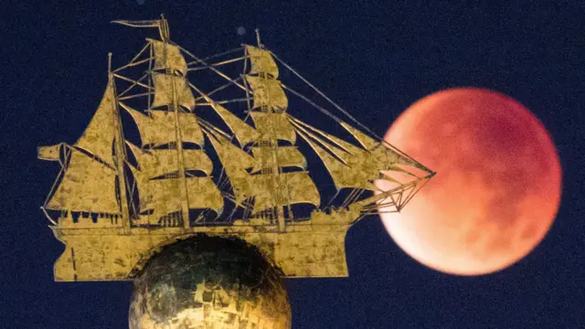 ماه پشت مجسمه یک کشتی در هامبورگ آلمان