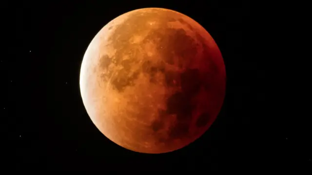 Gerhana bulan total terlihat berakhir saat Bulan keluar dari bayang-bayang Bumi pada 28 September 2015 di Glastonbury, Inggris. 
