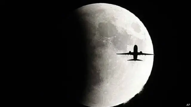 طائرة تطير أمام القمر العملاق فوق مدينة جنيف السويسرية