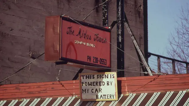 Надпись на плакате: "Эта вывеска светится благодаря аккумулятору моего автомобиля"