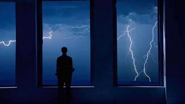 Человек перед окном, за которым молнии
