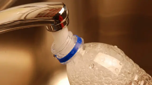 Botella de plástico llenándose con agua del grifo