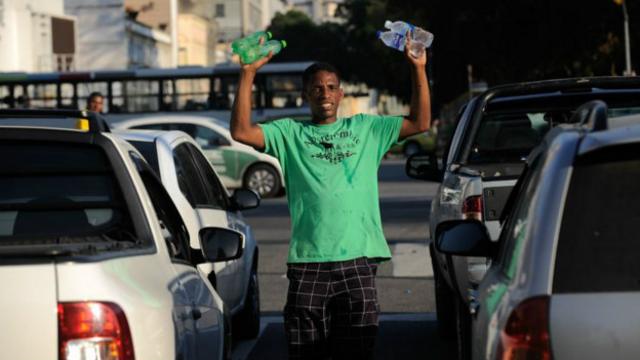 Ambulantes aproveitam para ganhar dinheiro vendendo água para refrescar o calor no trânsito